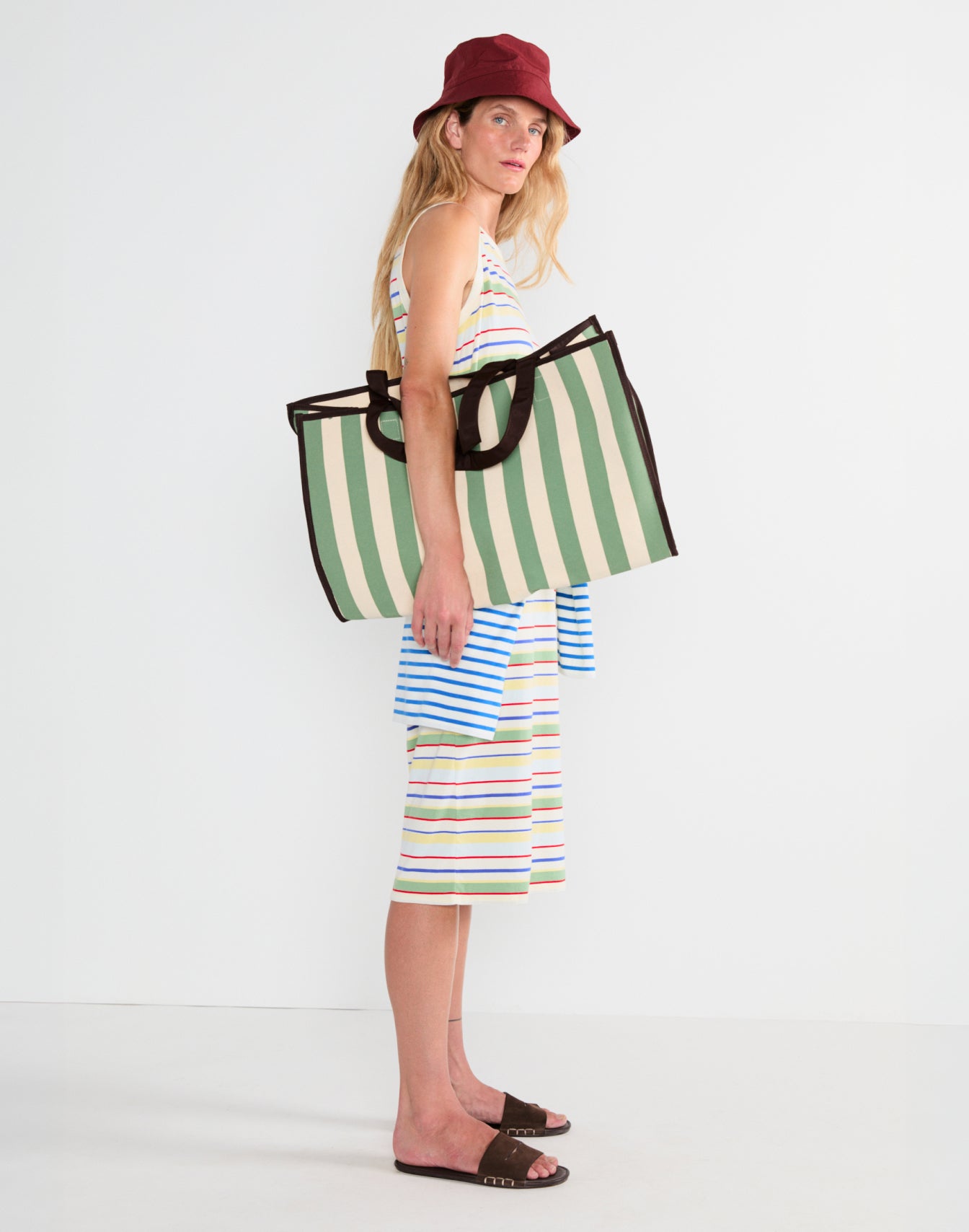 Model wearing The Tank Dress - Rainbow Multistripe and holding The Lucia - Sage/Canvas